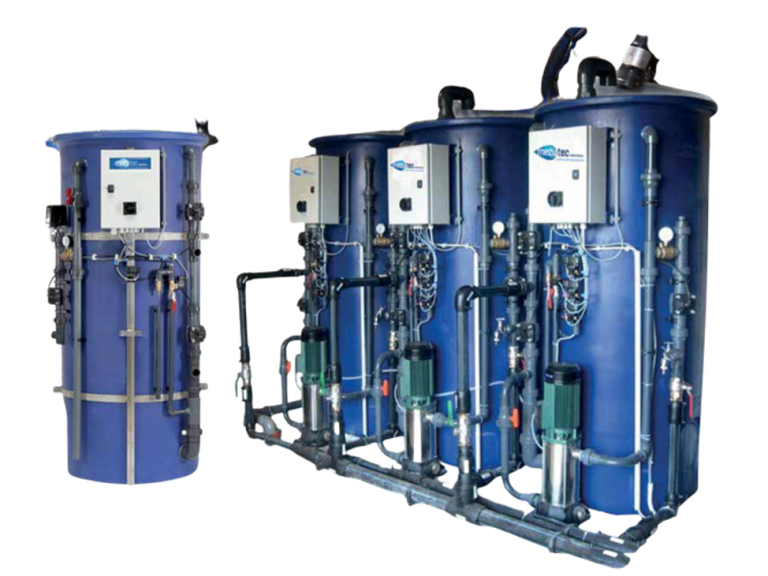 Vier Industrietanks mit blauen Außenwänden, versehen mit diversen Rohren, Ventilen und Bedienfeldern, stehen in einer Reihe. Die Tanks sind Teil eines komplexen Systems zur Brunnenwasseraufbereitung oder möglicherweise zur Wasserbehandlung.