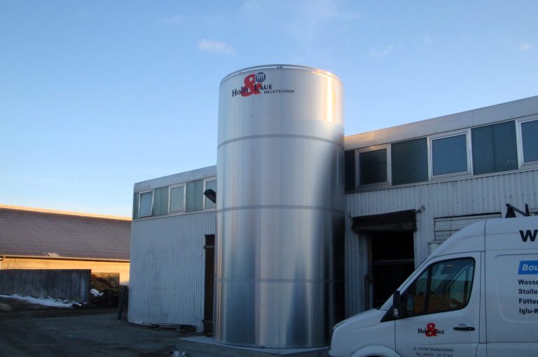 Stallungen mit einem Milchkühlsilo im Vordergrund und einem Service-Auto danaben.